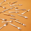 Cutlery. Pop art style. Flat lay of variety of stainless steel, silver and golden forks arranged over orange studio