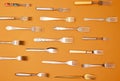 Cutlery. Top view flat lay photo of variety of antique silverware and gold forks arranged over orange studio background.