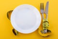 Cutlery and a white plate with measuring tape on a yellow background Royalty Free Stock Photo