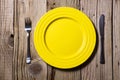 Cutlery and yellow plate on wooden