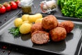 Cutlet with boiled potatoes on a black plate