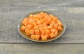 Cuts cubes of carrot in black plate on wooden rustic Royalty Free Stock Photo