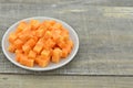 Cuts cubes of carrot in white plate on wooden nature Royalty Free Stock Photo