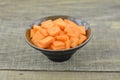 Cuts slices carrots in black bowl on wooden table Royalty Free Stock Photo