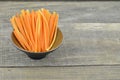 Cuts stick carrots in black bowl on wooden table, closeup Royalty Free Stock Photo