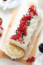 Cutted sponge biscuit cake roll filling whipped cream and berries decorated strawberry, blueberry and red currants on white