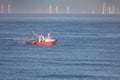 A cutter with lifted drag nets on the North sea with wind turbines in the background Royalty Free Stock Photo