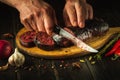 Cutting blood sausage with a knife in hands of a cook on a cutting board. Cooking a national dish on the kitchen table with Royalty Free Stock Photo