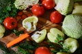 Cutting board with cabbage, tomato, carrot, pepper vegetables, dill, parsley greenery and a knife cutting a white bell pepper Royalty Free Stock Photo