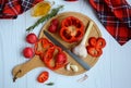 Cutting board with chopped bell pepper, garlic, radish, sauce and rosemary on a light wooden table