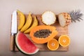 A cutting board with cut fruit on top and a knife, a papaya, a watermelon, a pineapple, oranges and bananas Royalty Free Stock Photo