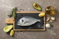 Cutting board with Dorado fish and cooking ingredients on background, top view Royalty Free Stock Photo