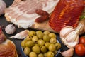 Cutting board with jamon, prosciutto, bacon, salami and chorizo on dark wooden background.