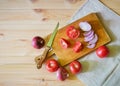 Cutting board, knife, pieces of tomato and slices of onion on wooden background Royalty Free Stock Photo