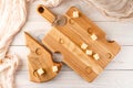 Cutting board made of light wood with cheese-like holes on a dark wooden background