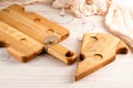 Cutting board made of light wood with cheese-like holes on a dark wooden background