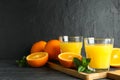 Cutting board with orange juice, mint and oranges on wooden table against black background, space for text Royalty Free Stock Photo