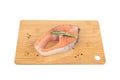 Cutting board with portioned salmon steak, rosemary and pepper on a white background.