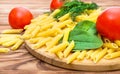 Cutting board with raw pasta, tomatoes, spinach and dill on wooden table. Cooking food Royalty Free Stock Photo