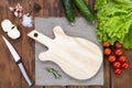 Cutting board in the shape of a guitar on a wooden table. Handmade chopping board. Fresh tomatoes, cucumbers and a cutting board. Royalty Free Stock Photo