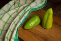 Cutting board with two green bell pepper and green kitchen towel on wooden background Royalty Free Stock Photo