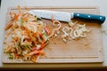 cutting board with vegetable peelings and a used knife