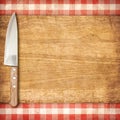 Cutting breadboard and knife over red grunge gingham tablecloth