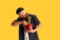 Comic portrait of stylish red-bearded man, barber in black cap having fun isolated over yellow background. Concept of