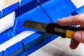 Cutting the corner of ceiling moldings from white polystyrene foam with a clerical knife using a box to cut corners. Royalty Free Stock Photo