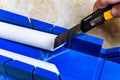 Cutting the corner of ceiling moldings from white polystyrene foam with a clerical knife using a box to cut corners. Royalty Free Stock Photo