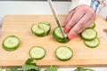 Cutting cucumbers into small pieces for preparing salad on a kitchen wooden cutting board. Royalty Free Stock Photo
