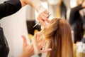 Cutting female blonde hair. Hairdresser cuts hair of a young caucasian woman in a beauty salon close up. Royalty Free Stock Photo