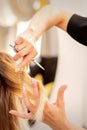 Cutting female blonde hair. Hairdresser cuts hair of a young caucasian woman in a beauty salon close up. Royalty Free Stock Photo