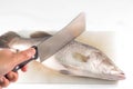 Cutting fish with a knife on cutting board.