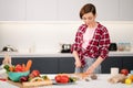 Cutting fresh carrot housewife cooking stew meat or ragout wearing a plaid shirt. Cooking with passion young woman with