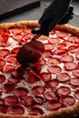 Cutting giant pepperoni pizza with special knife Royalty Free Stock Photo