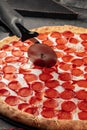 Cutting giant pepperoni pizza with special knife Royalty Free Stock Photo