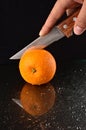 Cutting a fresh orange with knife Royalty Free Stock Photo