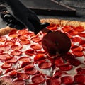 Cutting giant pepperoni pizza with special knife Royalty Free Stock Photo