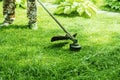 Cutting grass in the garden with a trimmer. Lawn improvement works in landscape design. Selective focus Royalty Free Stock Photo