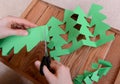 Cutting green card into a chain of Christmas trees