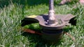 Cutting green grass with whipper snipper. Hand held grass trimmer mowing lawn. Grass shreds flying around in slow-mo