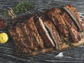 Cutting grilled pork ribs with sauce on a board,  spices, wooden background Royalty Free Stock Photo