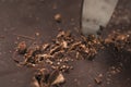 Cutting industrial block of dark chocolate with knife