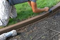 Concrete curb edging being troweled for smoothness in a flower bed