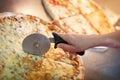 Cutting margarita pizza on slices with special knife Royalty Free Stock Photo