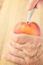 Cutting a peach with a paring knife Royalty Free Stock Photo