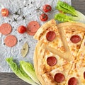 Cutting pizza with salami and melted cheese on wooden background with tomatoes, slices of sausage and lettuce around it Royalty Free Stock Photo