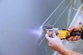 Cutting plasterboard with using multi tool for laying an electric cable in the wall Royalty Free Stock Photo