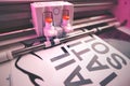 cutting plotter equiped with two adjustable blades makes adhesive lettering from black vinyl foil in energetic pink light